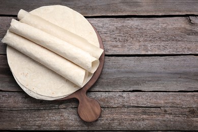 Photo of Delicious rolled Armenian lavash on wooden table, top view. Space for text