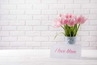 Photo of Composition with greeting card and tulips for Mother's Day on table