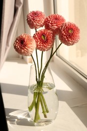 Photo of Bouquet of beautiful dahlia flowers in vase on windowsill indoors