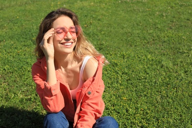 Photo of Portrait of happy woman with heart shaped glasses on green lawn