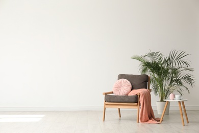 Photo of Stylish living room interior with comfortable armchair and houseplant white wall. Space for text