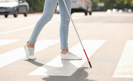 Photo of Blind person with long cane crossing road, closeup