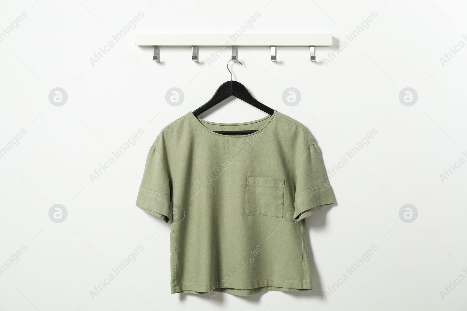 Photo of Hanger with olive t-shirt on white wall