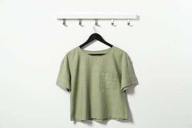 Hanger with olive t-shirt on white wall