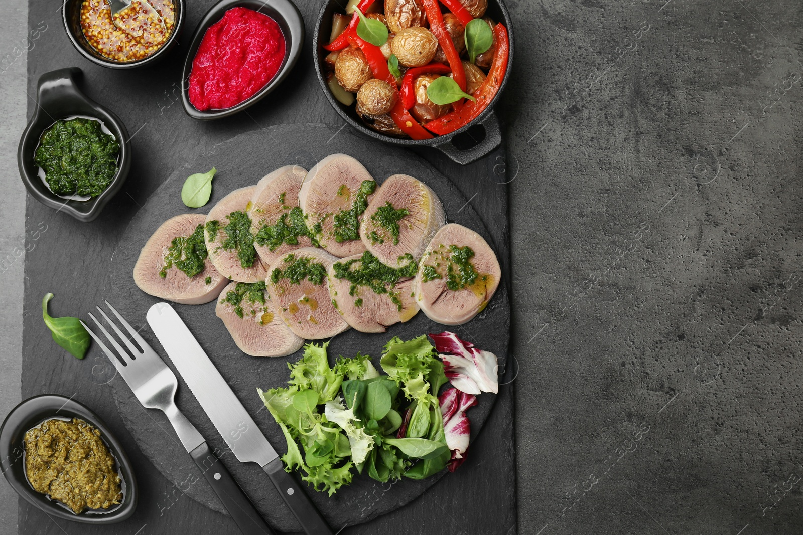 Photo of Tasty beef tongue pieces and ingredients served on grey table, top view. Space for text