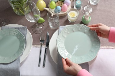 Photo of Woman setting table for festive Easter dinner at home, above view
