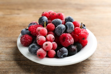 Mix of tasty frozen berries on wooden table