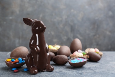 Photo of Chocolate Easter bunny and eggs on grey table. Space for text