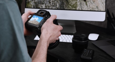 Image of Man with professional photo camera looking at shot of mountain indoors, closeup. Banner design