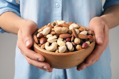 Photo of Woman holding bowl with organic mixed nuts, closeup