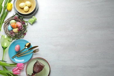 Festive Easter table setting with painted eggs on wooden background, top view. Space for text