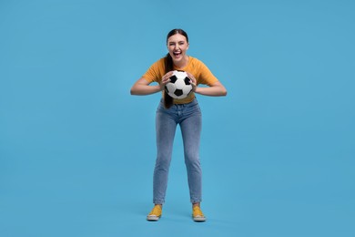 Photo of Happy soccer fan with ball on light blue background