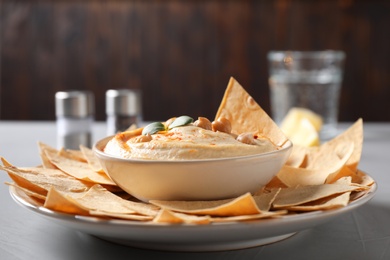 Photo of Delicious creamy hummus served with chips on table