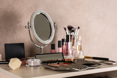 Photo of Dressing table with beauty accessories near color wall in room