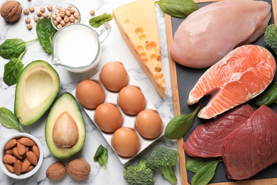 Photo of Set of natural food high in protein on marble background, top view