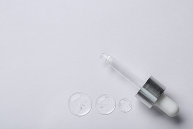 Pipette with samples of cosmetic serum on white background, flat lay. Space for text