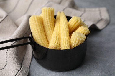 Tasty fresh yellow baby corns in dish on grey table, closeup