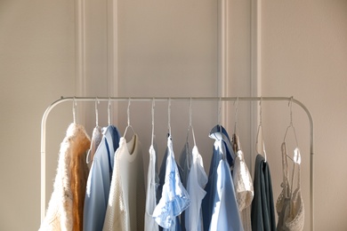 Photo of Rack with stylish women's clothes near white wall. Interior design