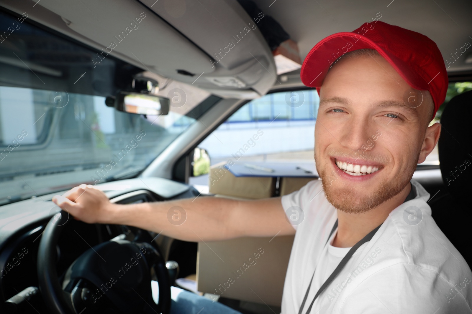 Photo of Young courier with parcels in delivery car