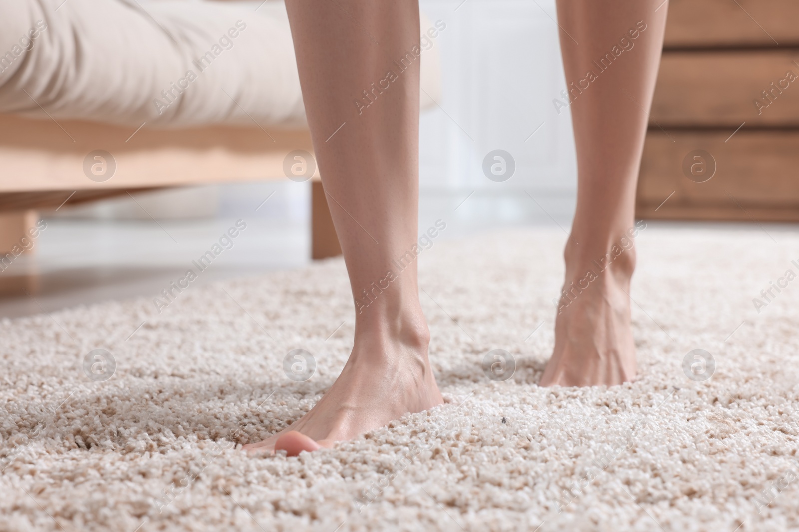 Photo of Woman walking on soft light brown carpet at home, closeup