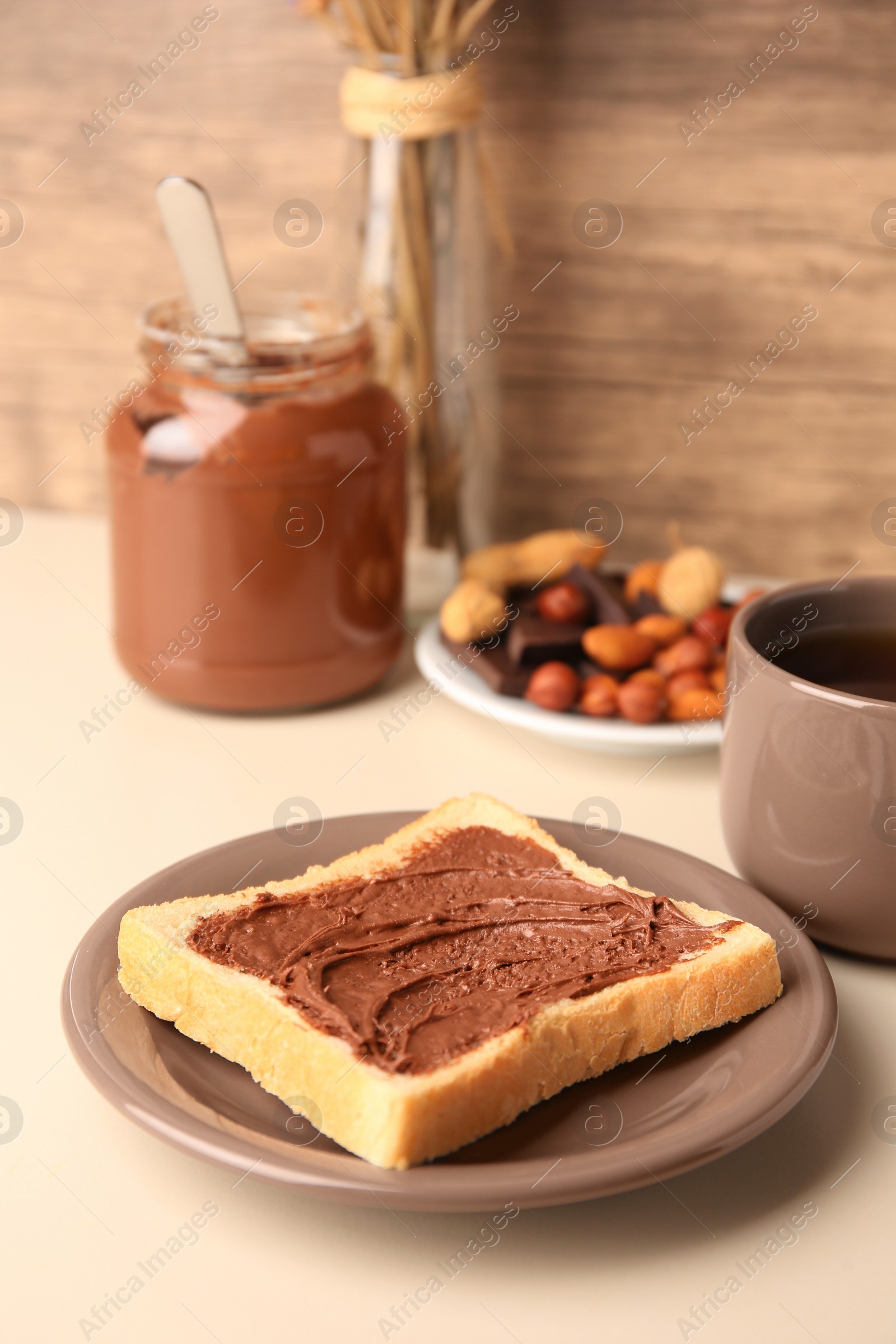 Photo of Tasty toast with chocolate paste and cup of tea served on light table