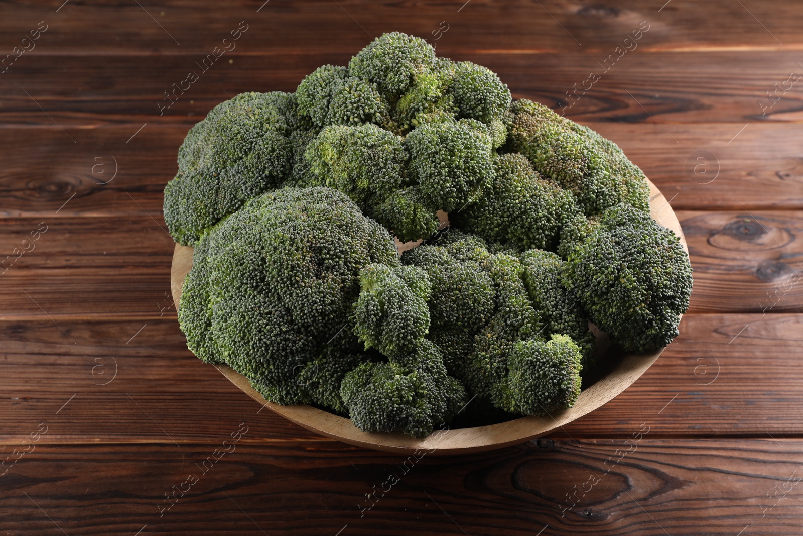 Photo of Bowl of fresh raw broccoli on wooden table