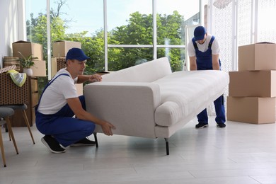 Photo of Moving service employees carrying sofa in room