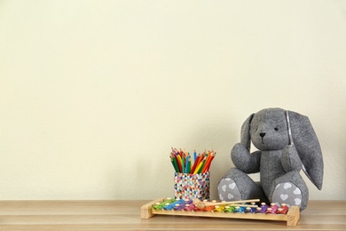 Toys and holder with color pencils for baby room interior on wooden table near light wall