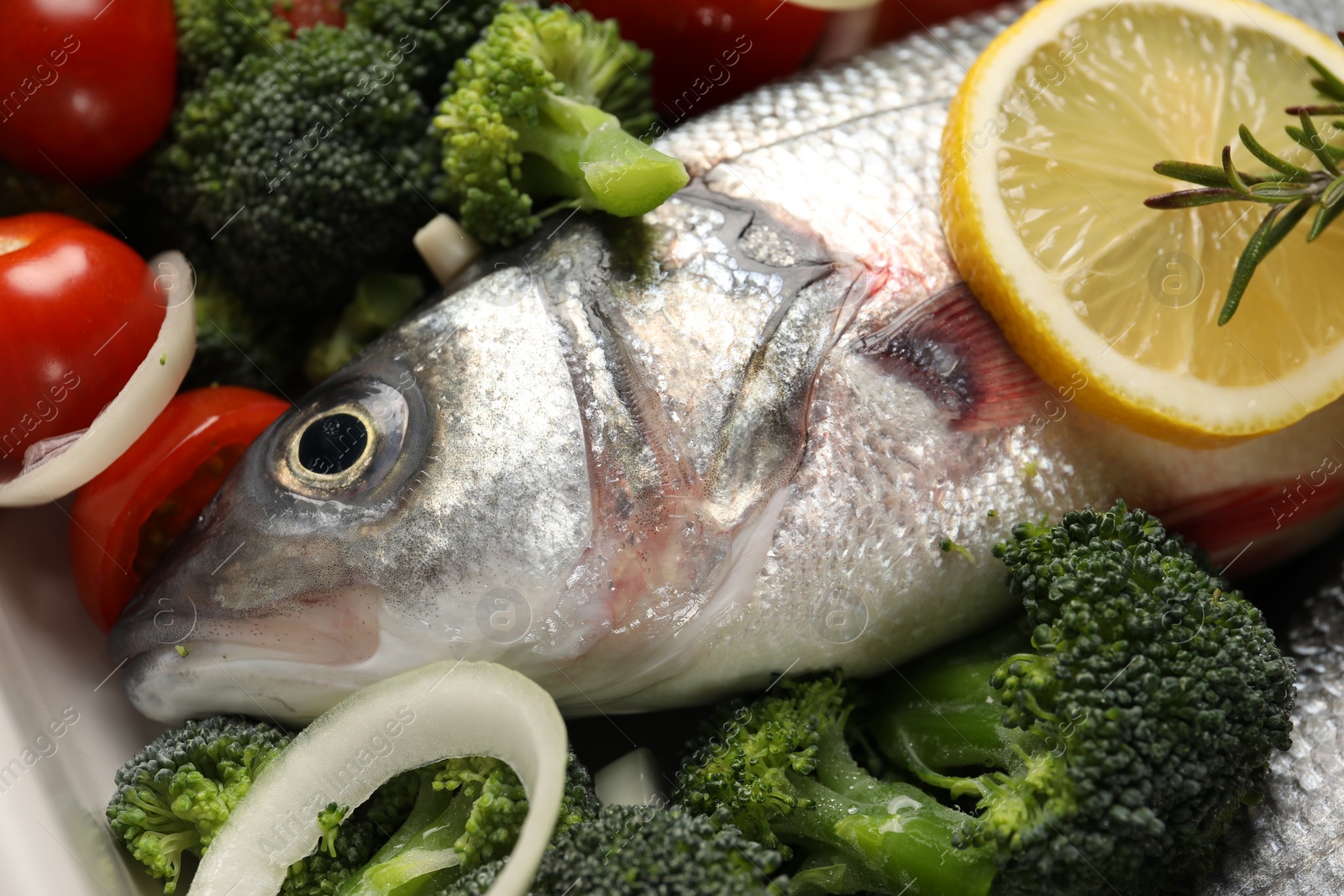 Photo of Raw fish with vegetables and lemon in baking dish, closeup