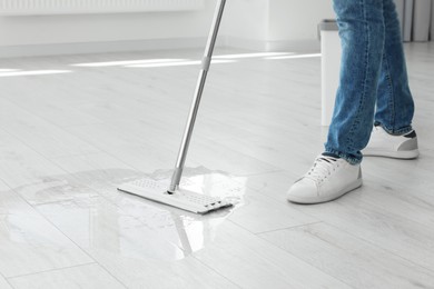 Photo of Man cleaning floor with mop indoors, closeup