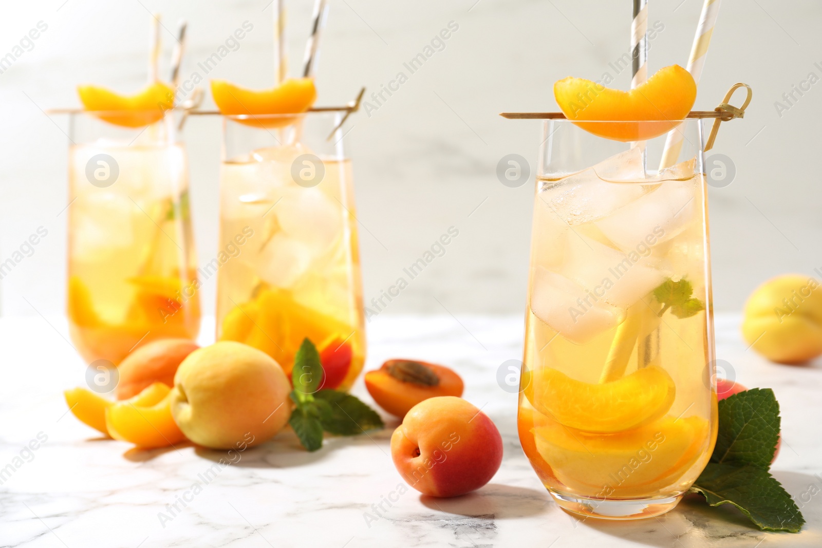 Photo of Delicious refreshing drink with apricot on white marble table