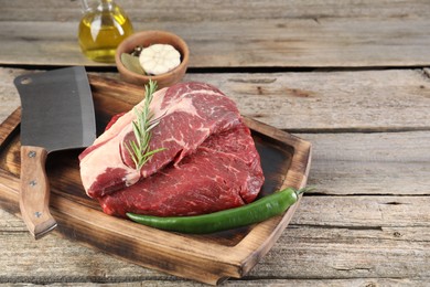 Photo of Fresh raw beef cut, spices and butcher knife on wooden table. Space for text