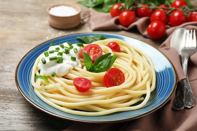 Photo of Delicious spaghetti with sour cream on wooden table