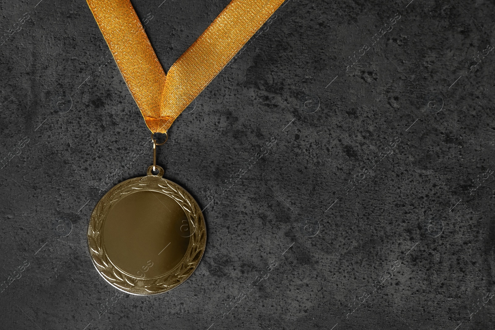 Photo of Gold medal on grey stone background, top view. Space for design