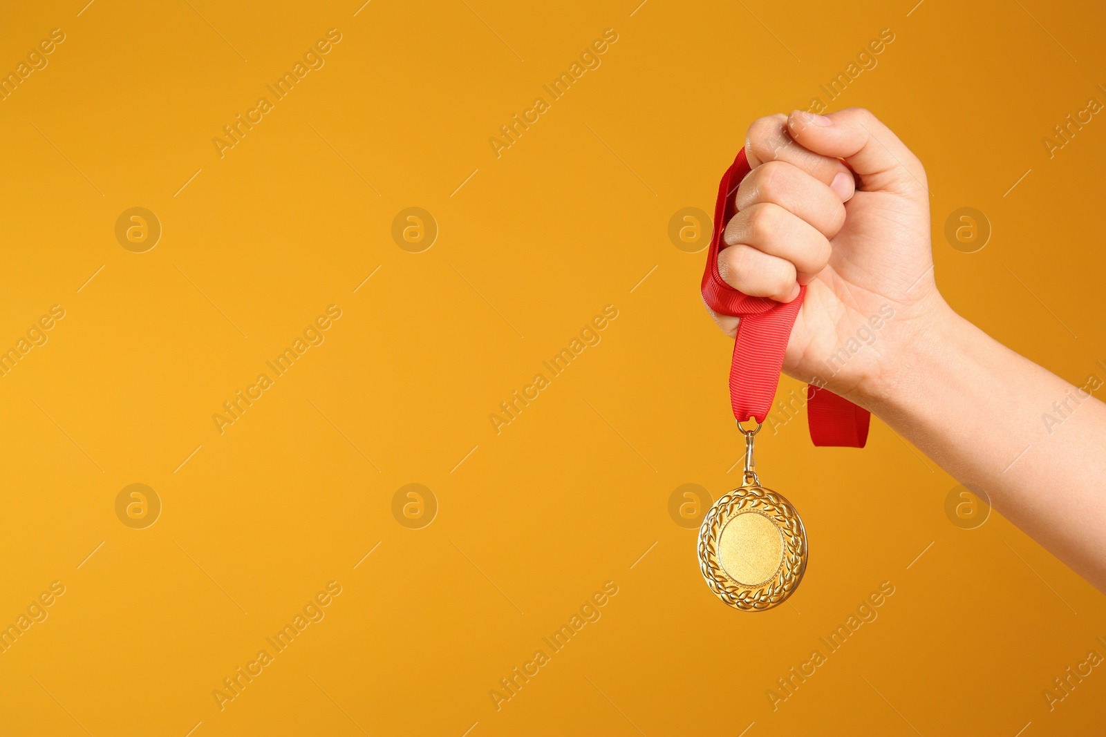 Photo of Woman holding gold medal on yellow background, closeup. Space for text