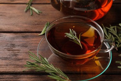 Photo of Aromatic herbal tea with rosemary on wooden table, space for text