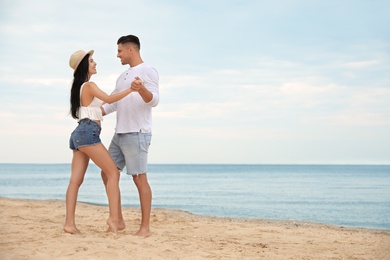 Photo of Lovely couple dancing on beach near sea. Space for text