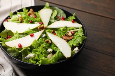 Photo of Delicious pear salad in bowl on wooden table, closeup