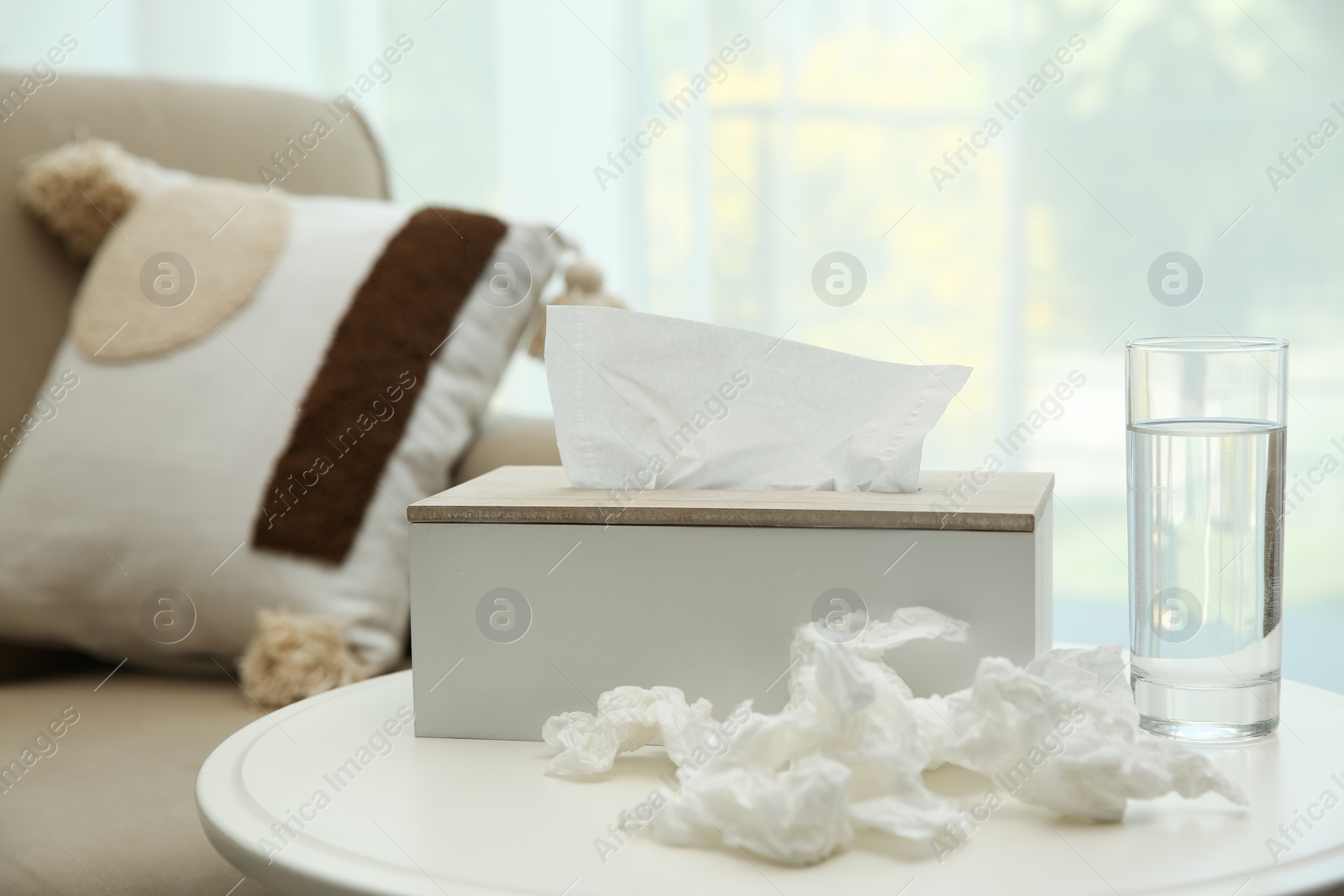 Photo of Used paper tissues, holder and water on table indoors