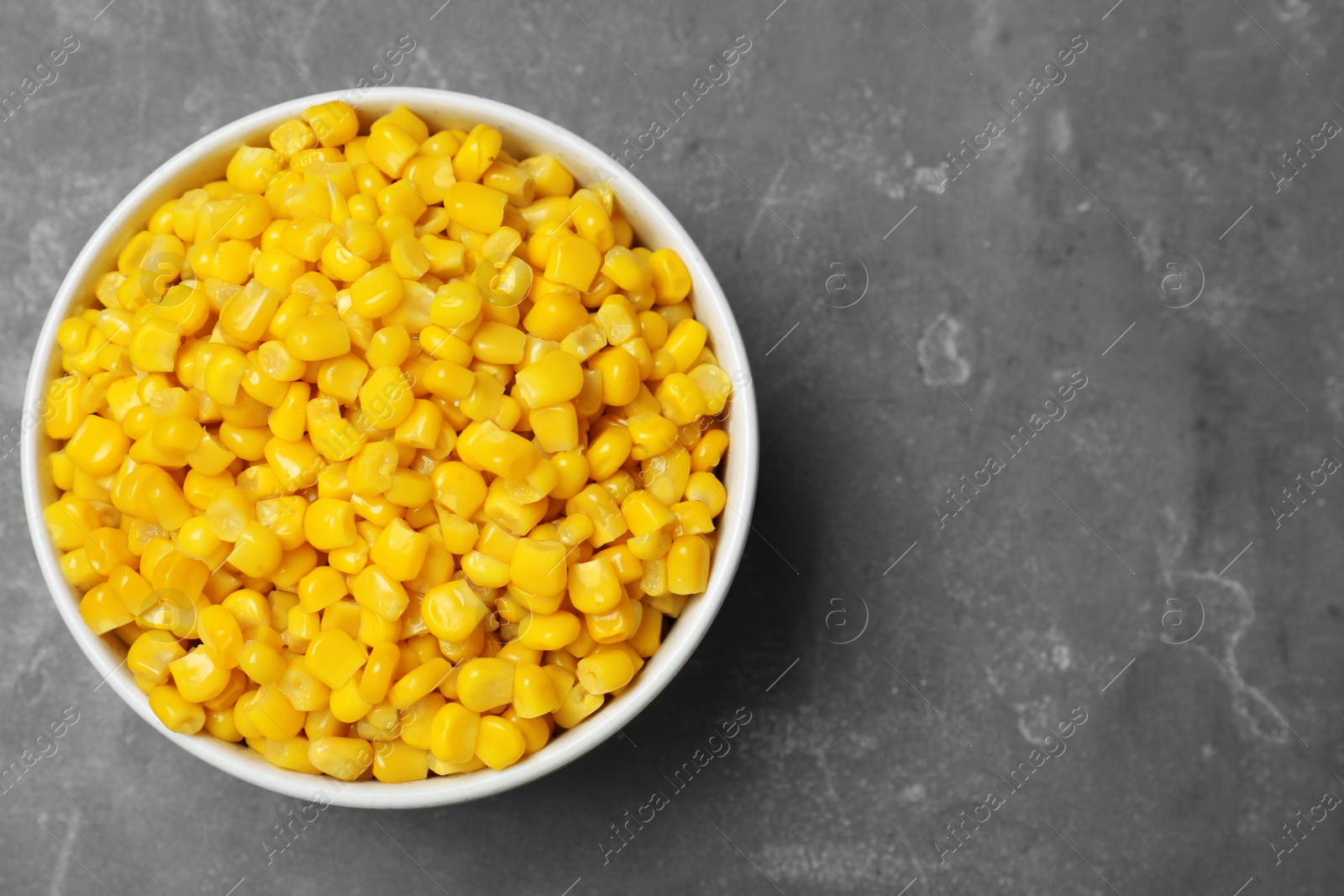 Photo of Delicious canned corn in bowl on grey table, top view