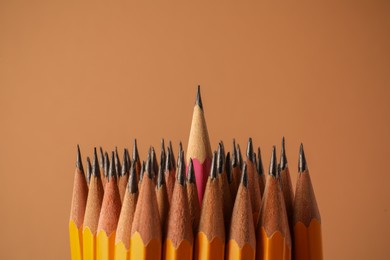 Photo of Many sharp graphite pencils on brown background