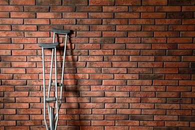 Pair of axillary crutches near red brick wall. Space for text