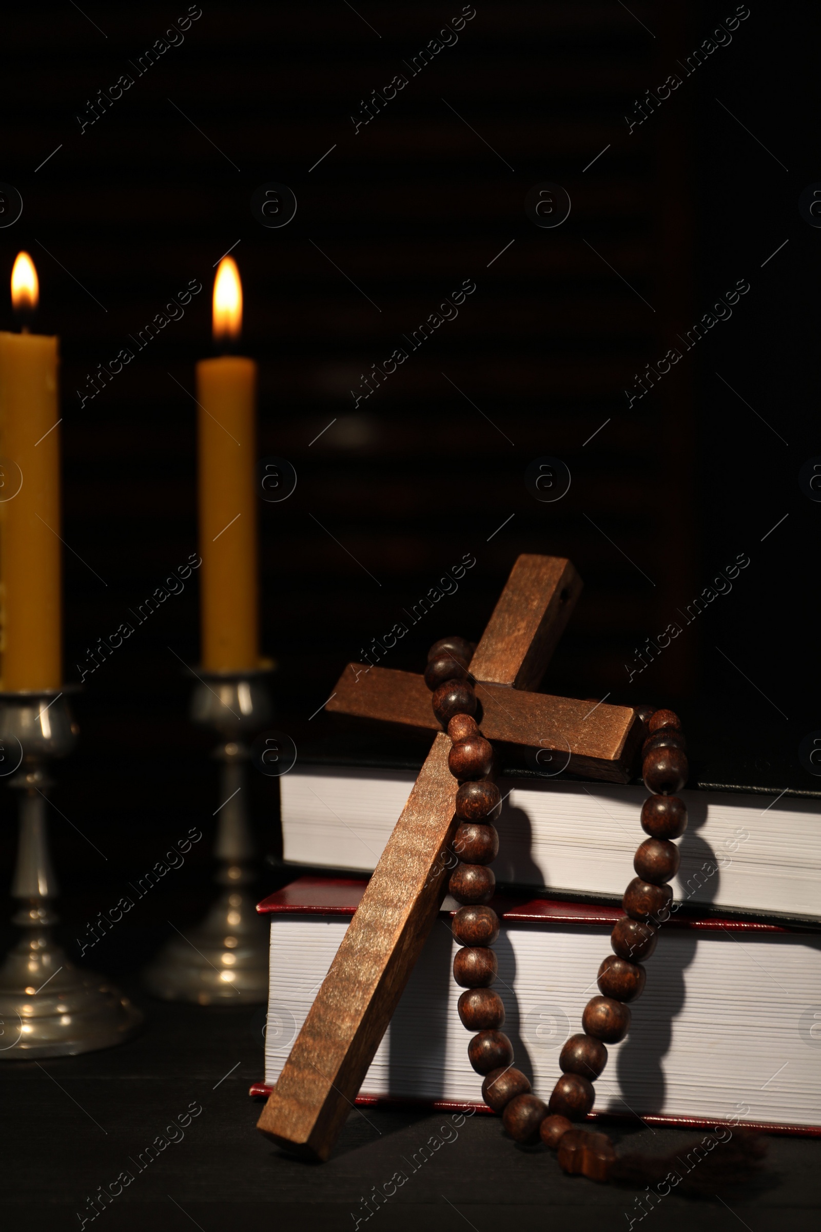 Photo of Church candles, Bible, rosary beads and cross on wooden table