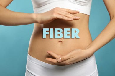 Image of Woman holding hands near belly and word Fiber, closeup