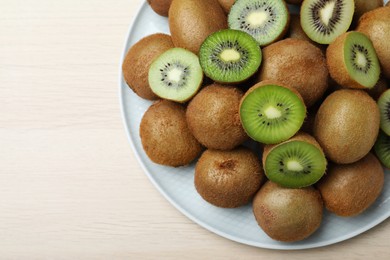 Photo of Fresh ripe kiwis on light wooden table, top view. Space for text