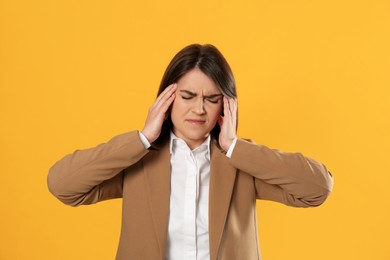 Young woman suffering from migraine on yellow background