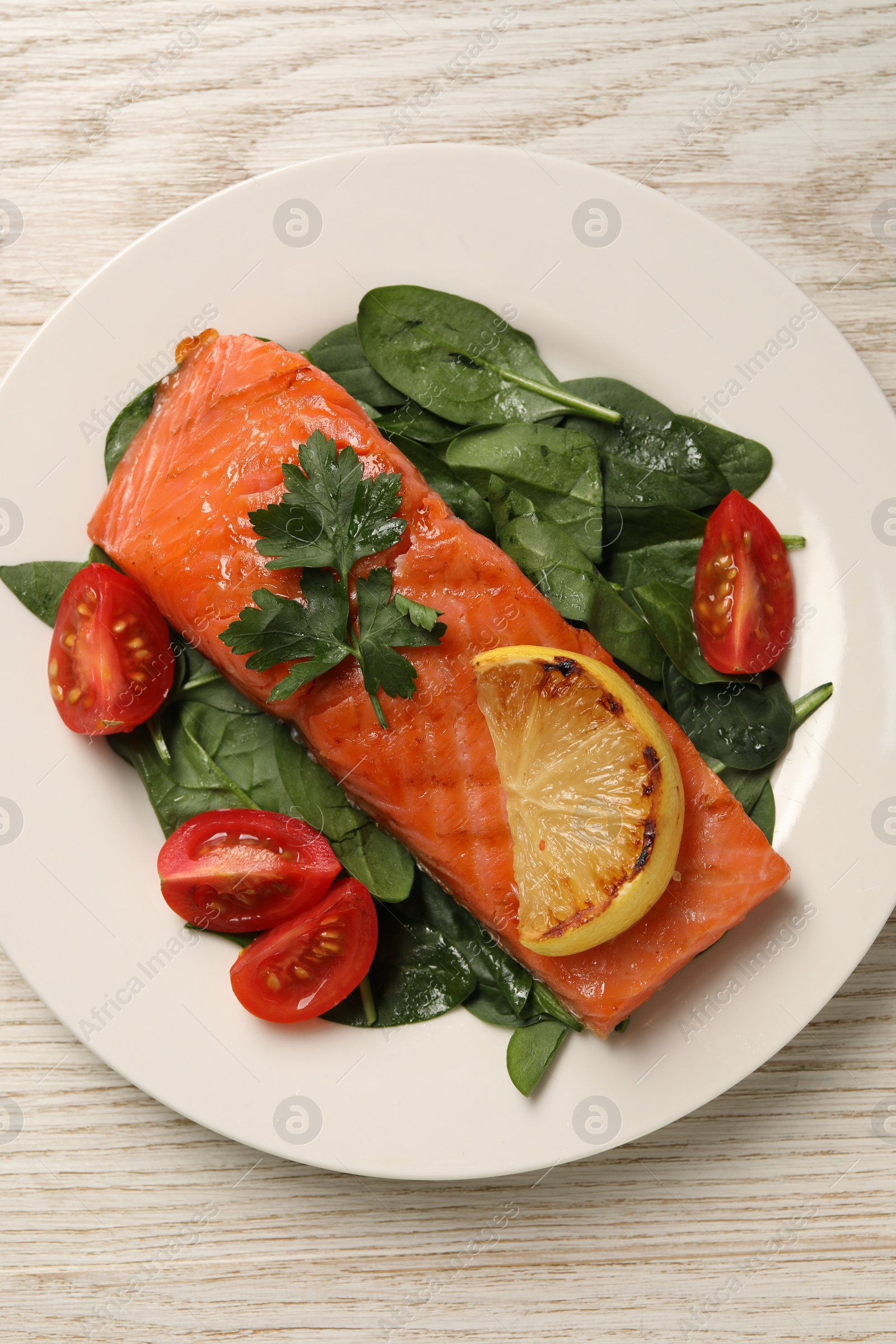 Photo of Tasty grilled salmon with tomatoes, lemon and basil on white wooden table, top view