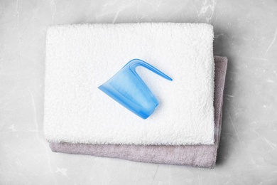 Photo of Clean towels and measuring cup on marble background, flat lay