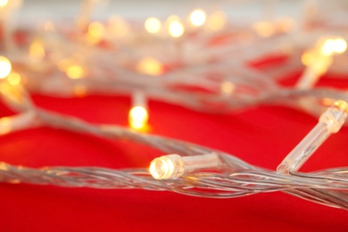 Photo of Glowing Christmas lights on color background, closeup