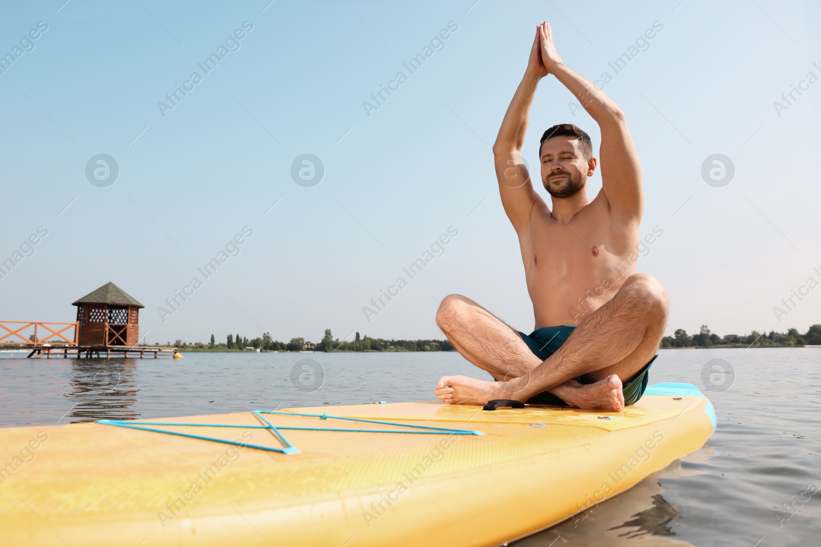 Photo of Man practicing yoga on SUP board on river